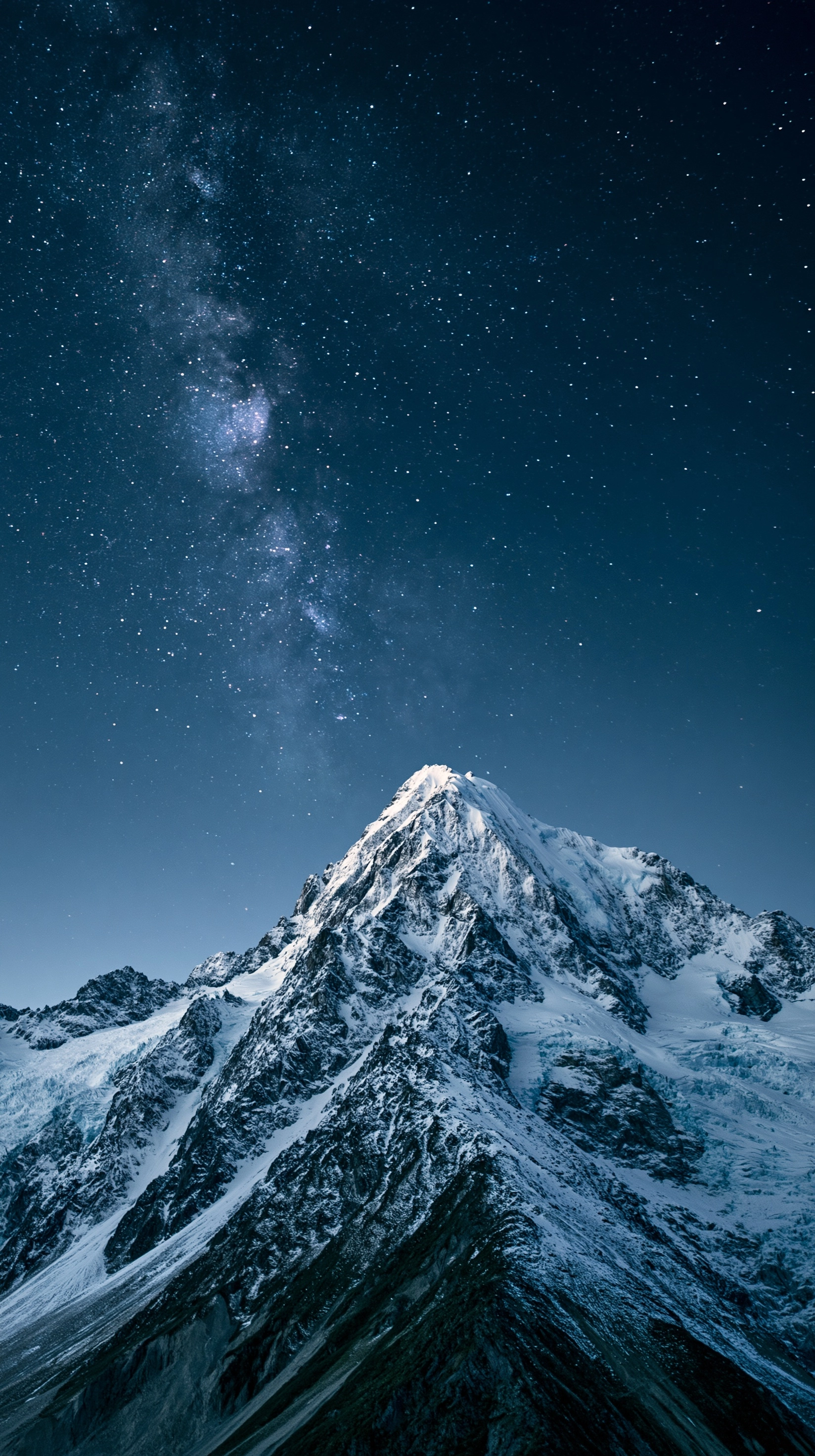a full shot of a snowy mountain under a dark, starry night sky. the milky way is visible in the uppe